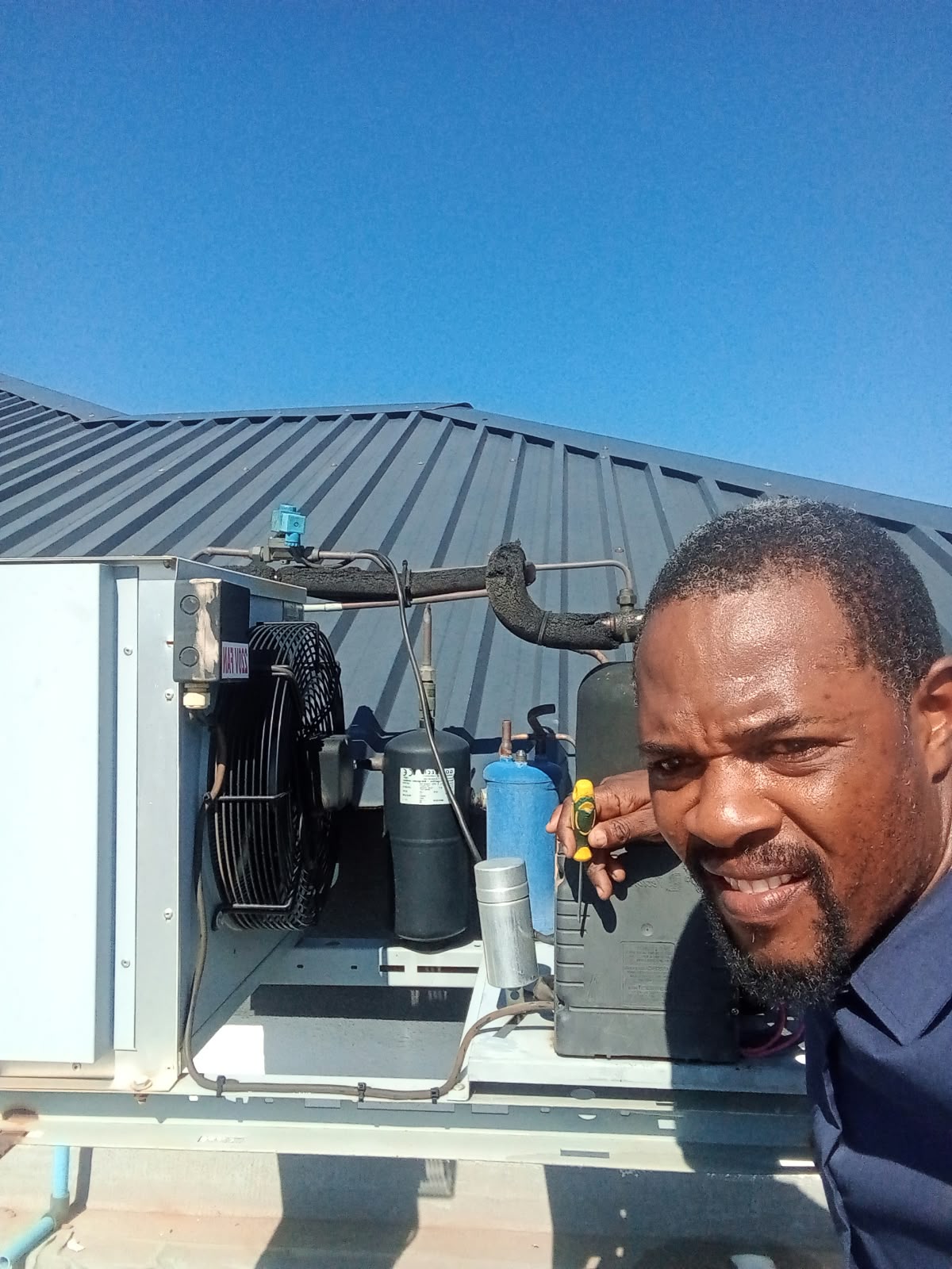 Technician repairing a condenser unit on a roof
