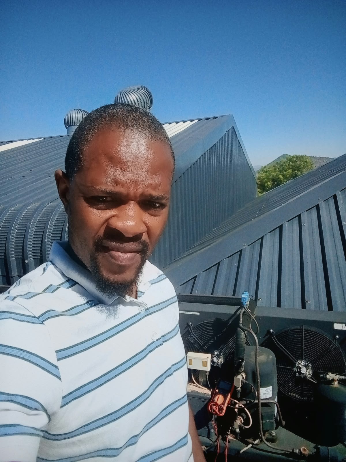 Technician on site next to rooftop refrigeration equipment