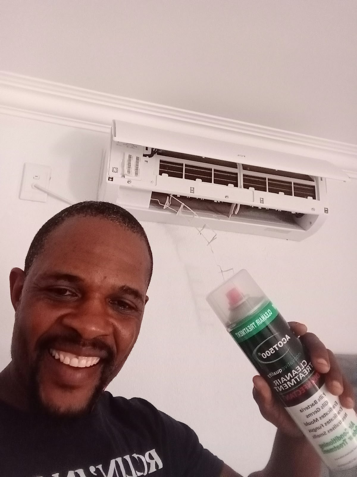 Technician topping up aircon gas beside a split unit