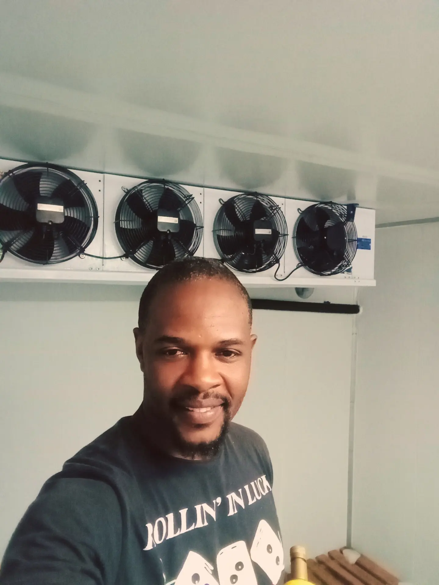 Technician inside a cold room with evaporator fan units overhead