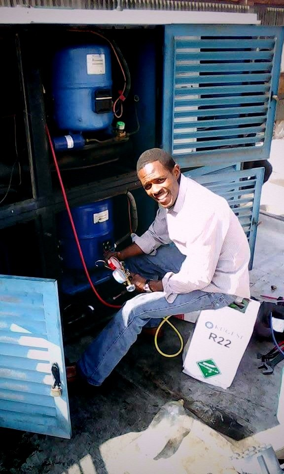 Technician recharging a commercial refrigeration compressor with R22 gas